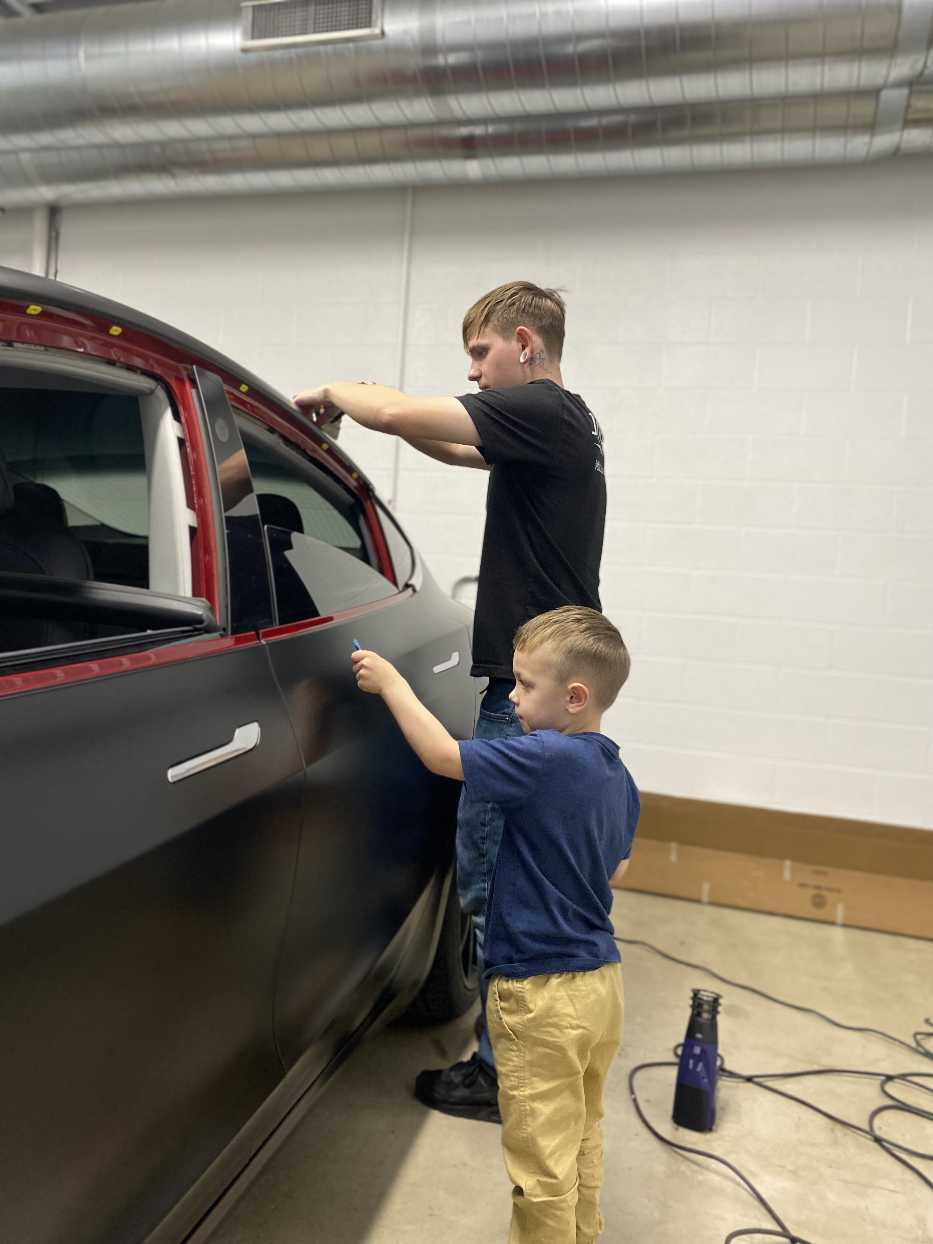 Allyn wrapping a car in the early garage days with his son helping