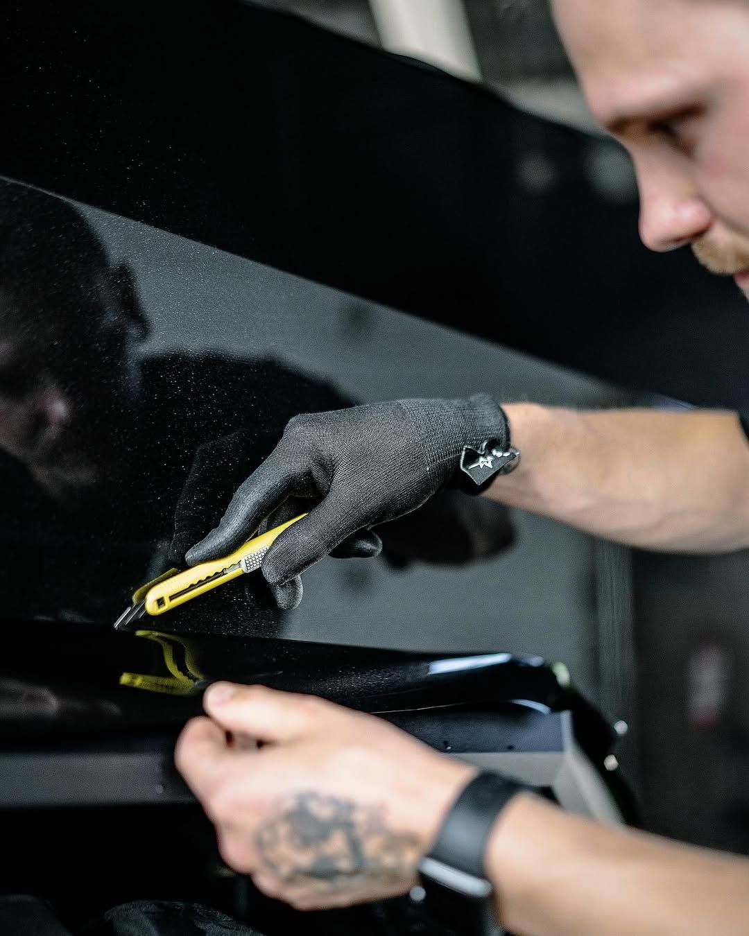 Installer working film onto a vehicle panel