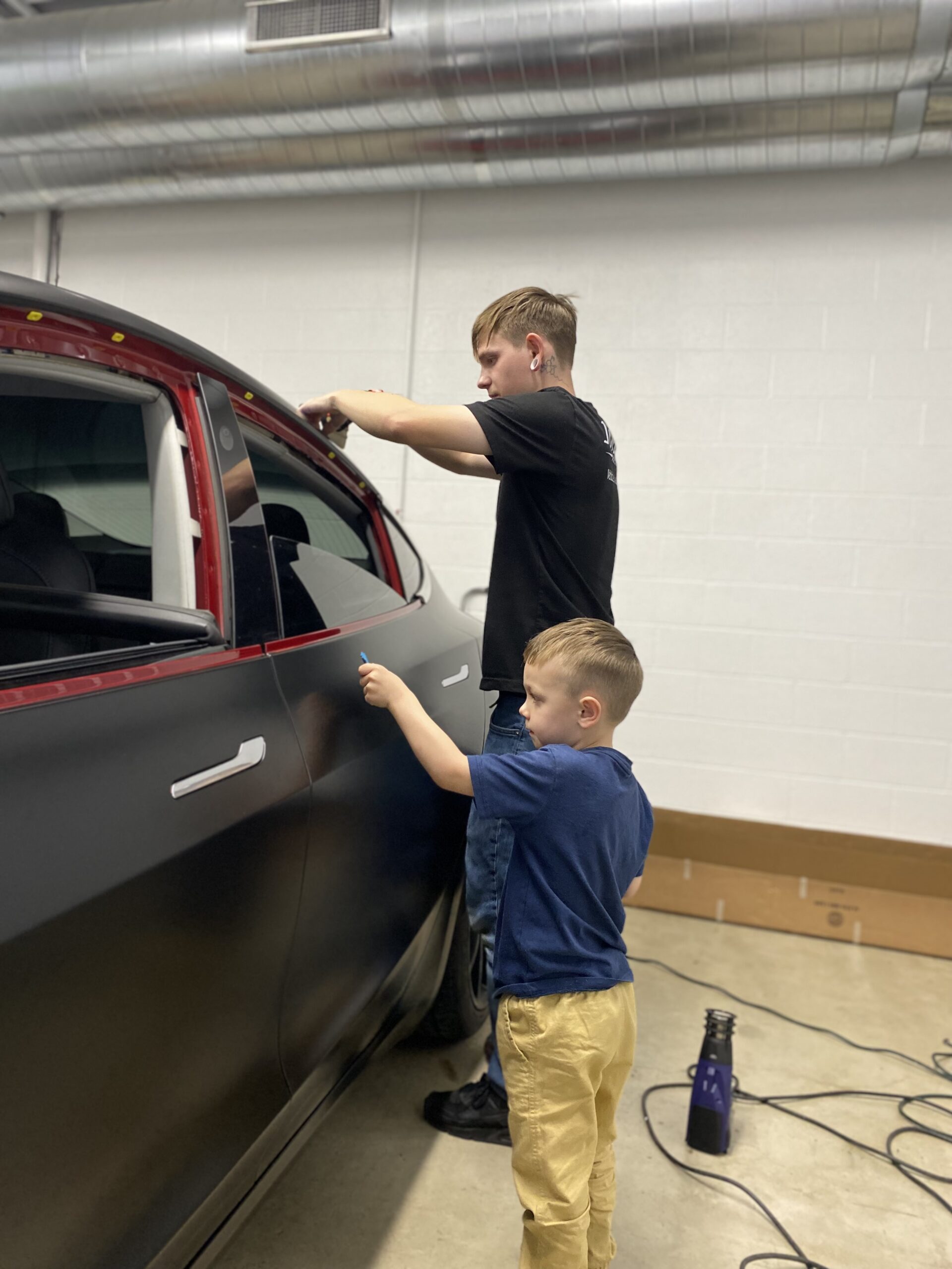Allyn wrapping a car in the early garage days with his son helping