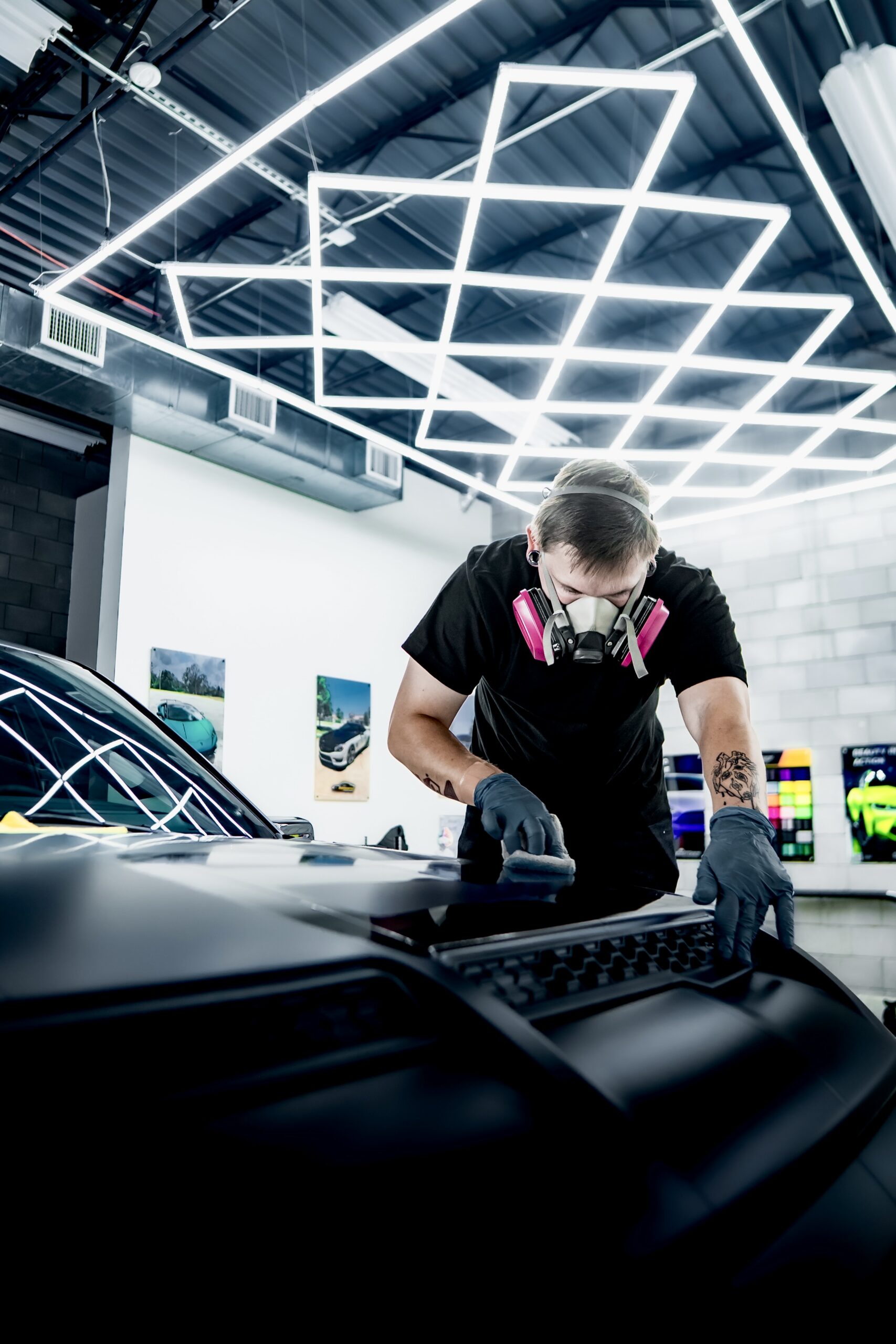 Installer applying a ceramic coating to a black hood at the Wraps Redefined studio