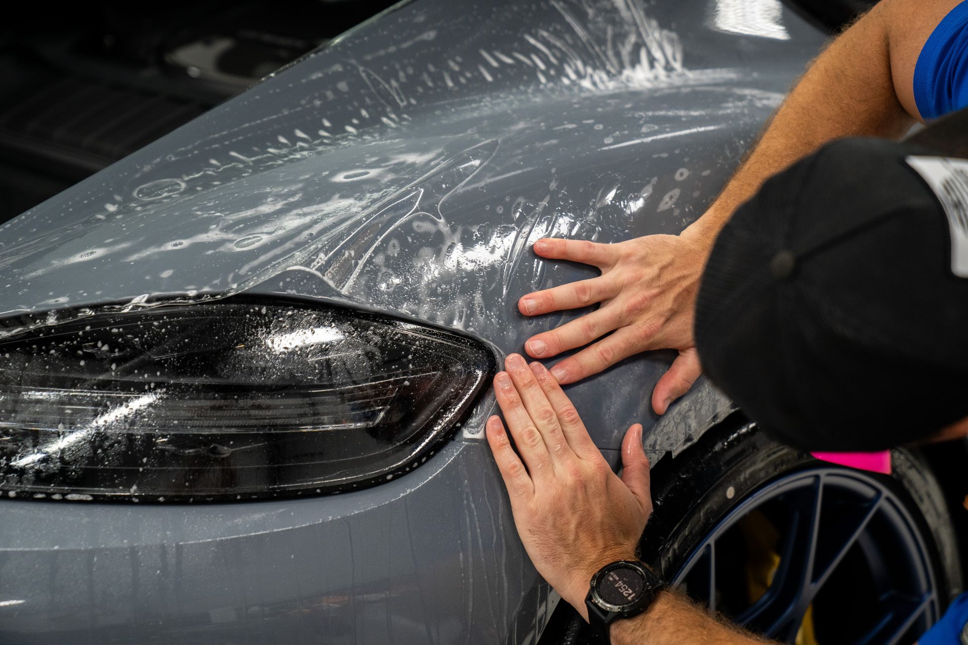 Installer smoothing clear paint protection film over a fender at the Wraps Redefined studio